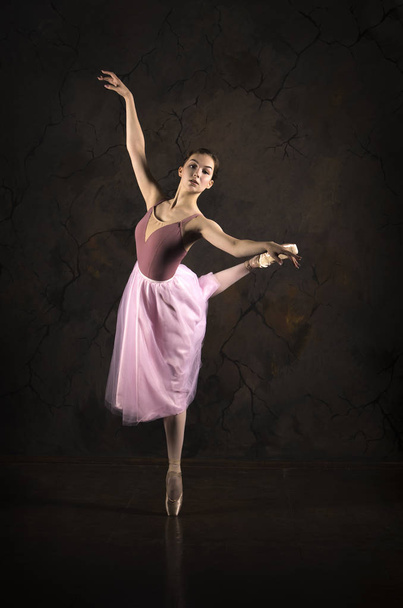 A slender girl in a pink skirt and beige top dancing ballet. - Valokuva, kuva