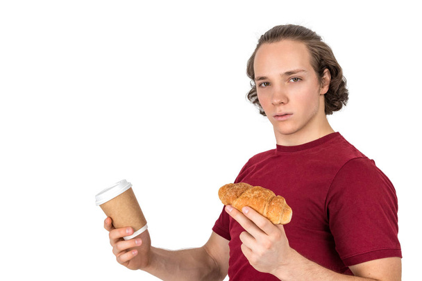 Young handsome man drink coffee and eating croissant. French breakfast and morning coffee. Isolated - Fotó, kép