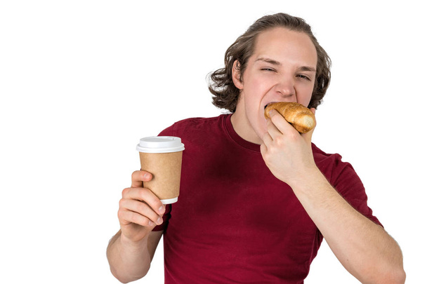 Young handsome man drink coffee and eating croissant. French breakfast and morning coffee. Isolated - Φωτογραφία, εικόνα
