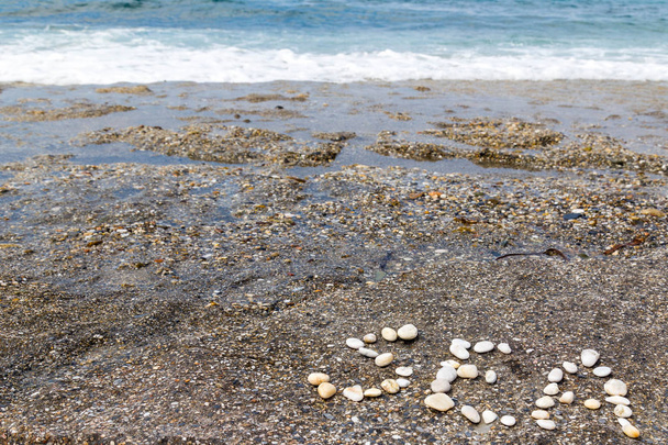 suuret kirjaimet sana "meri" pienillä kivillä meren rannikolla
 - Valokuva, kuva