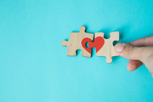 Női kéz összekötő puzzle húzott vörös szívvel kék háttér. Szerelmi koncepció. St. Valentin nap. Egyeztetés. Reunion koncepció. Lemezterület másolása. - Fotó, kép