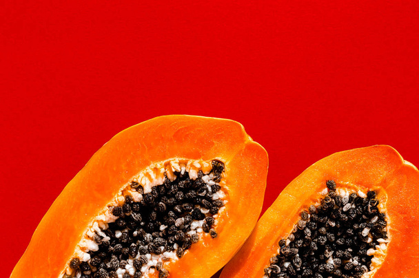 Fresh papaya exotic tropical fruit on red background. Sun day light illumination. Minimalistic summer flat lay wallpaper. Creative food concept. Copy space template. - Foto, immagini