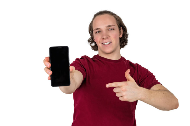 Handsome young man in t-shirt holding blank screen smartphone over white background - Foto, Bild
