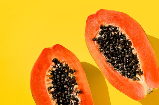 Fresh papaya exotic tropical fruit on yellow background. Sun day light illumination. Minimalistic summer flat lay wallpaper. Creative food concept. Copy space template. Bold colors - Photo, Image