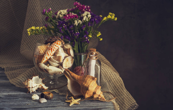A variety of seashells and  wild flowers on a wooden table - Фото, изображение
