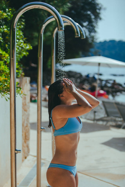 mujer tomando una ducha en la playa del mar. lavar el agua salada
 - Foto, Imagen