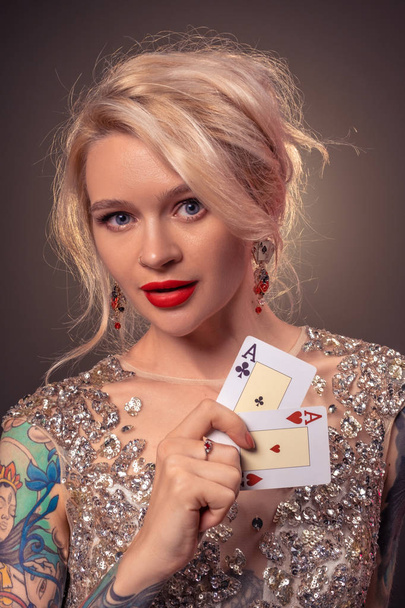 Blonde woman with a beautiful hairstyle and perfect make-up is posing with playing cards in her hands. Casino, poker. - Φωτογραφία, εικόνα