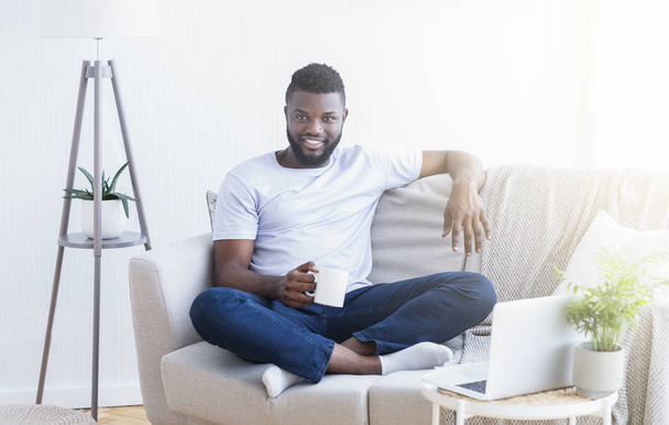 ホームオフィスで休息を楽しむ陽気なアフリカ人男性 - 写真・画像