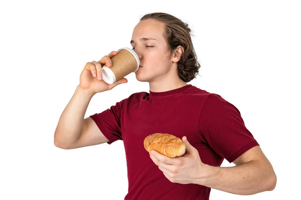 Young handsome man drink coffee and eating croissant. French breakfast and morning coffee. Isolated - Photo, Image