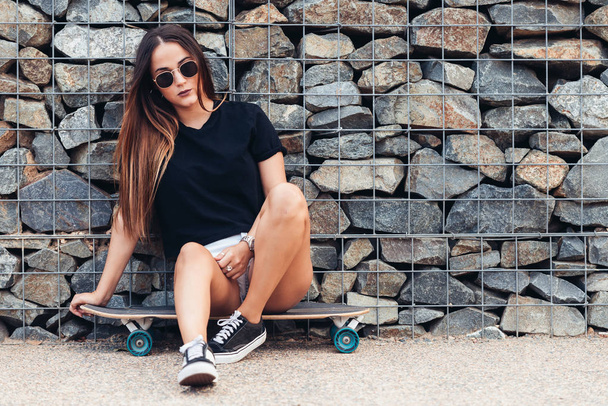 schöne junge Frau sitzt auf Skateboard  - Foto, Bild