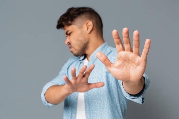 Disgusted man gesturing no with his hands on gray background - Photo, Image