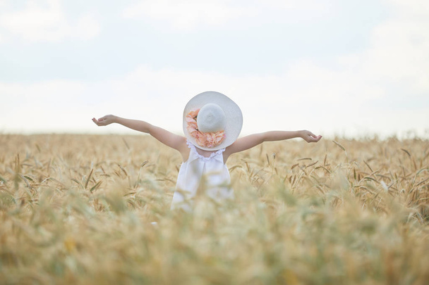 gündüz sırasında buğday alanında yükseltilmiş kollar ile şapkalı beyaz kadın - Fotoğraf, Görsel