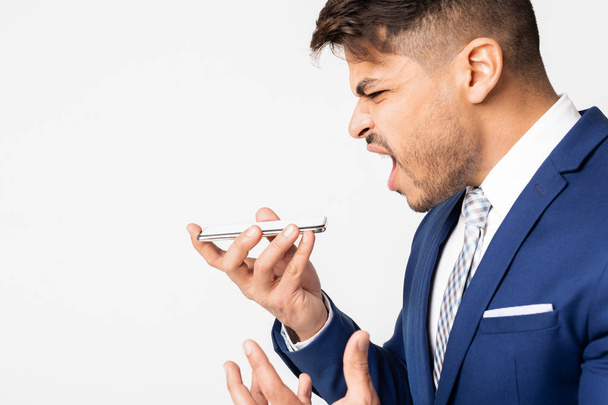 Portrait Of Angry Businessman Yelling At Smartphone Over White Background - Photo, Image