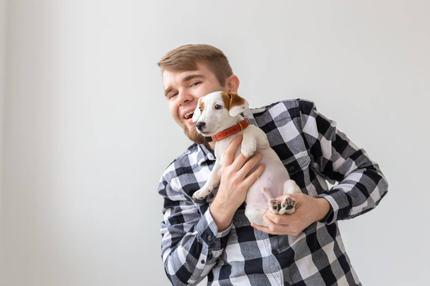 Concepto de personas, mascotas y perros - Hombre sonriente sobre fondo blanco sosteniendo cachorro Jack Russell Terrier
 - Foto, imagen