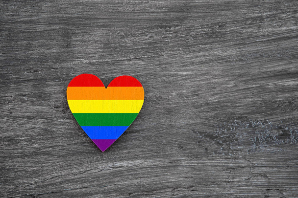 Dekorativní srdce s duhovými pruhy na šedém dřevěném pozadí. Vlajka LGBT. - Fotografie, Obrázek