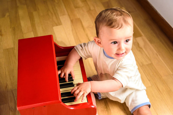 Baby learning to play the piano with a wooden toy instrument, a  - Φωτογραφία, εικόνα