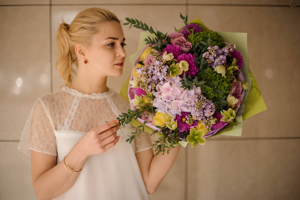 Girl holding a spring bouquet of tender green, yellow and violet flowers - Foto, immagini
