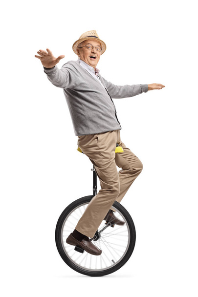 Excited elderly man riding a unicycle  - Valokuva, kuva