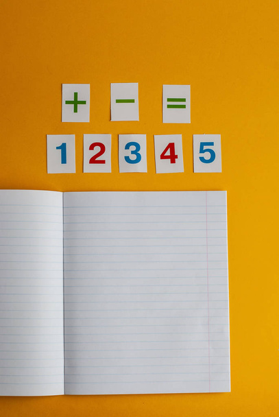 Cuaderno, números sobre fondo amarillo. Accesorios para estudio
. - Foto, Imagen