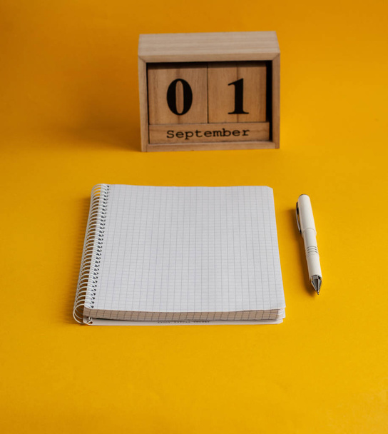 Notebook, white pen, wooden calendar with the date of September  - Фото, изображение