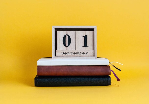 Wooden calendar with the date of September 1, stands on a stack  - Фото, изображение