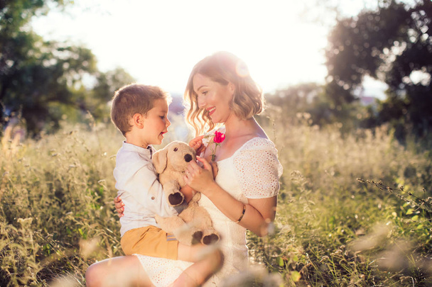 Счастливая юная леди с цветочным отдыхом в летнем парке. Широко улыбается с красной помадой на губах. Концепция Дня матери
 - Фото, изображение