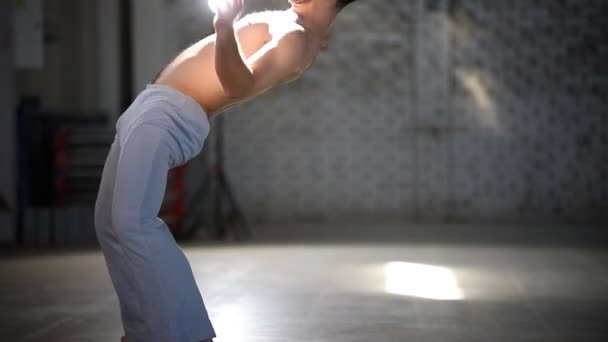 Hombre atlético haciendo elementos de capoeira en la habitación con piso de hormigón
 - Metraje, vídeo