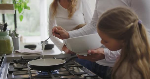 Side view of Caucasian family preparing food in kitchen at home. Father pouring ingredient in pan 4k - Filmmaterial, Video