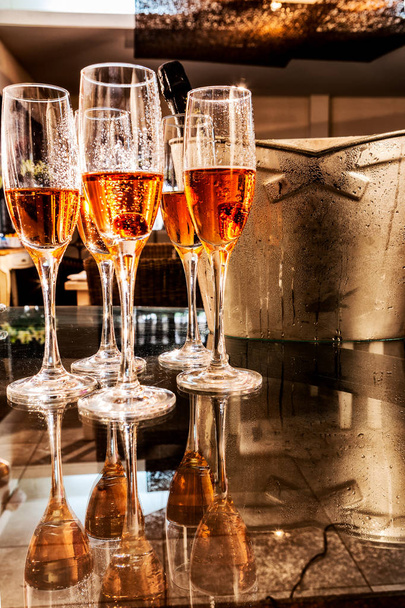 Verres de champagne avec frape et bouteille en arrière-plan, sur table avec réflexion
. - Photo, image