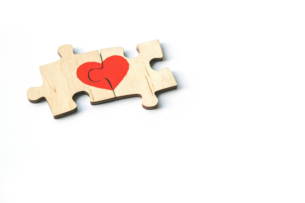 Red heart is drawn on the pieces of the wooden puzzle lying next to each other isolated on white background. Love concept. St. Valentine day. Copy space. - Fotó, kép