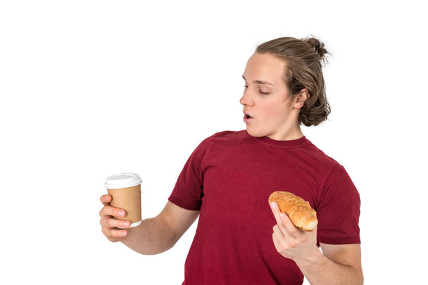 Young handsome man drink coffee and eating croissant. French breakfast and morning coffee. Isolated - Foto, Bild