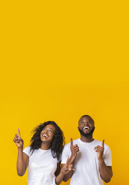 Happy african-american man and woman pointing fingers upwards - Photo, Image