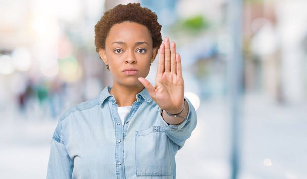 Young beautiful african american woman over isolated background doing stop sing with palm of the hand. Warning expression with negative and serious gesture on the face. - Фото, зображення