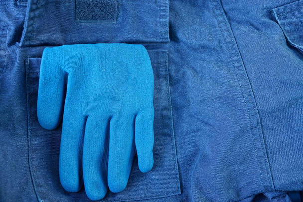 blue work glove in a pocket of crumpled fabric trousers - Photo, Image
