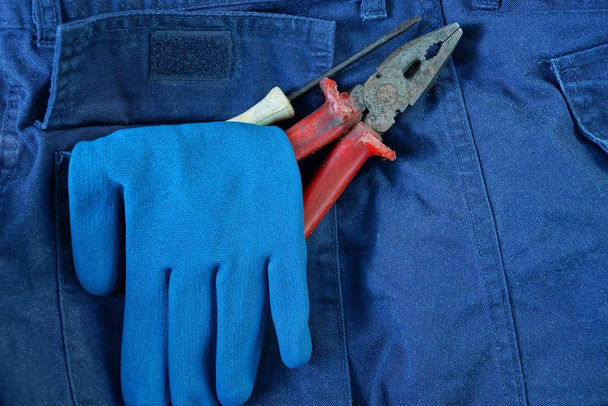 guante de trabajo azul y herramientas en el bolsillo de los pantalones
 - Foto, Imagen