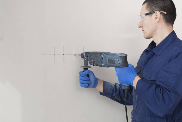 electrician worker drills a wall - Valokuva, kuva