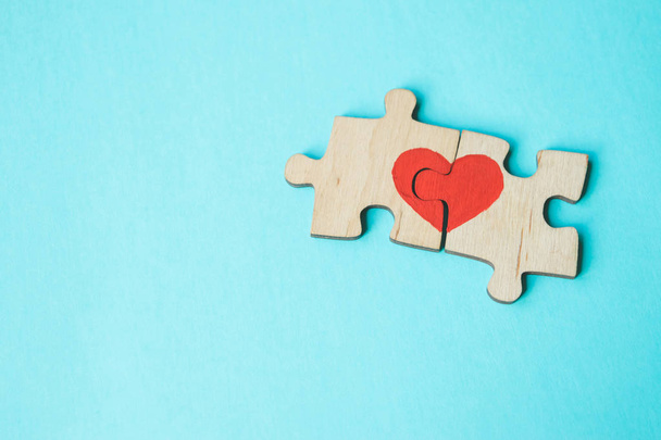 Vörös szív készül a darab a fából készült puzzle mellett fekvő egymást a kék háttér. Szerelmi koncepció. St. Valentin nap. Lemezterület másolása. - Fotó, kép