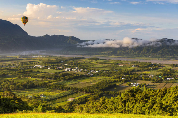 緑豊かな谷と山々の眺めと飛ぶ気球 - 写真・画像