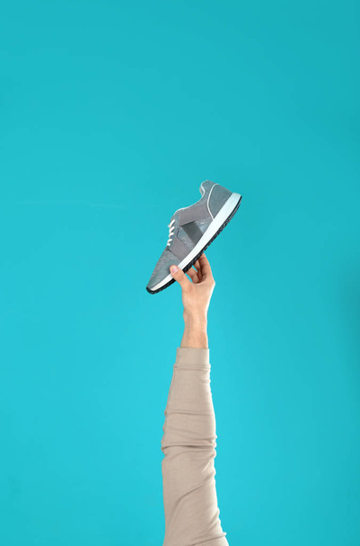 Young man holding comfortable shoe on light blue background, closeup - Photo, image