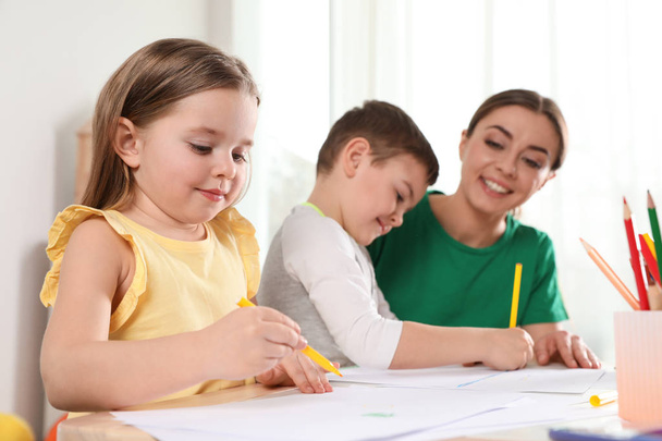 テーブルの上に幼稚園の先生が描かれている小さな子供たち。学習と遊び - 写真・画像