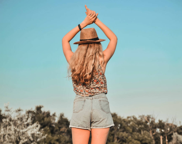 schöne junge Frau mit stylischem Hut mit sommerlichem Kaltgetränk hat Spaß im Freien. - Foto, Bild