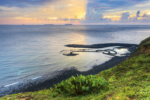colina verde en la orilla del océano con cielo nublado puesta de sol
 - Foto, Imagen