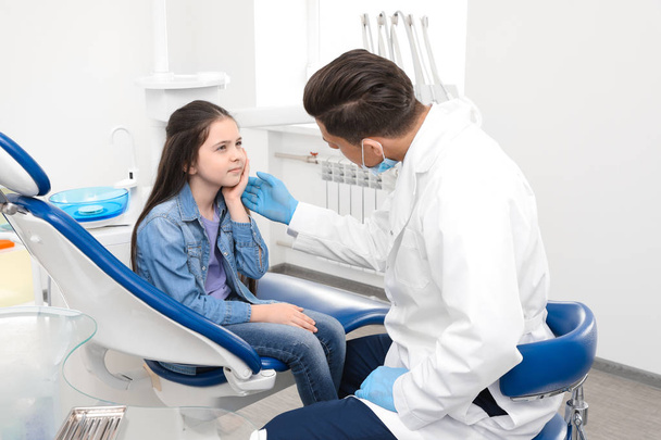 Професійний стоматолог, що працює з маленькою дівчинкою в клініці
 - Фото, зображення