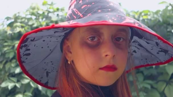 Halloween. Teen dziewczyna ubrana jako zła wiedźma, z czerwonymi ustami i siniaki pod oczami. - Materiał filmowy, wideo