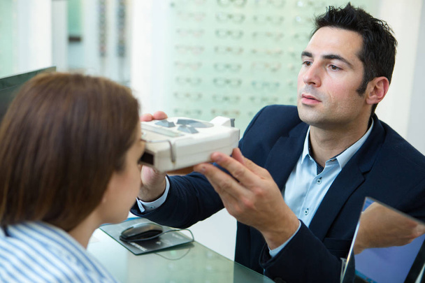 optometrist in exam room with woman in chair - 写真・画像
