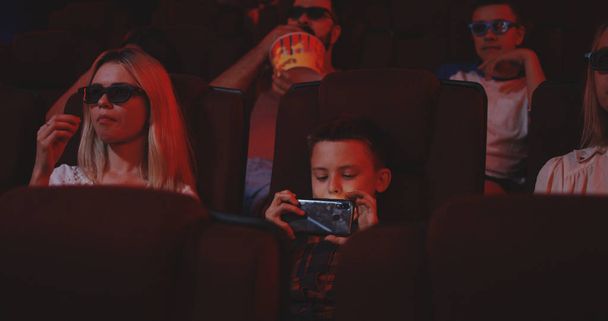 Boy pirating movie in cinema with smartphone - Photo, Image