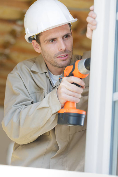 builder using cordless drill to install windows - Foto, afbeelding