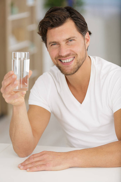 happy man showing a glass of water to the camera - Φωτογραφία, εικόνα