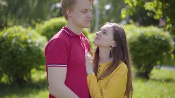 Heureux couple caucasien amoureux serrant tendrement et souriant sur le fond de parc vert de printemps. Romantique passer du temps à l'extérieur. Mouvement lent
. - Séquence, vidéo
