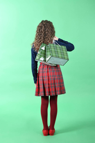 Child with a green packaging checkered texture isolated on green background. Girl likes shopping on sale season. Holiday present, shopping.  - Foto, imagen